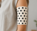 Person wearing a white piccline and midline cover with black polka dots against a neutral background